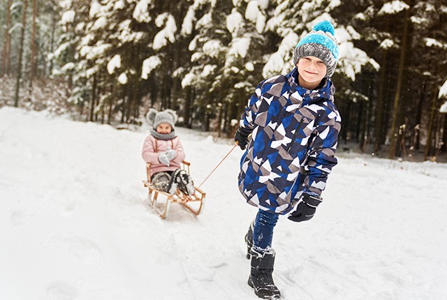 DE_boy pulling young girl on snow sled.